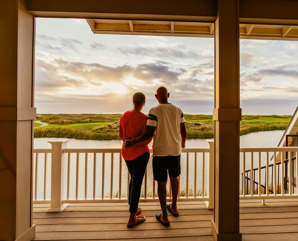 Couple on a covered porch overlooking the marsh at sunset at Palmilla Beach