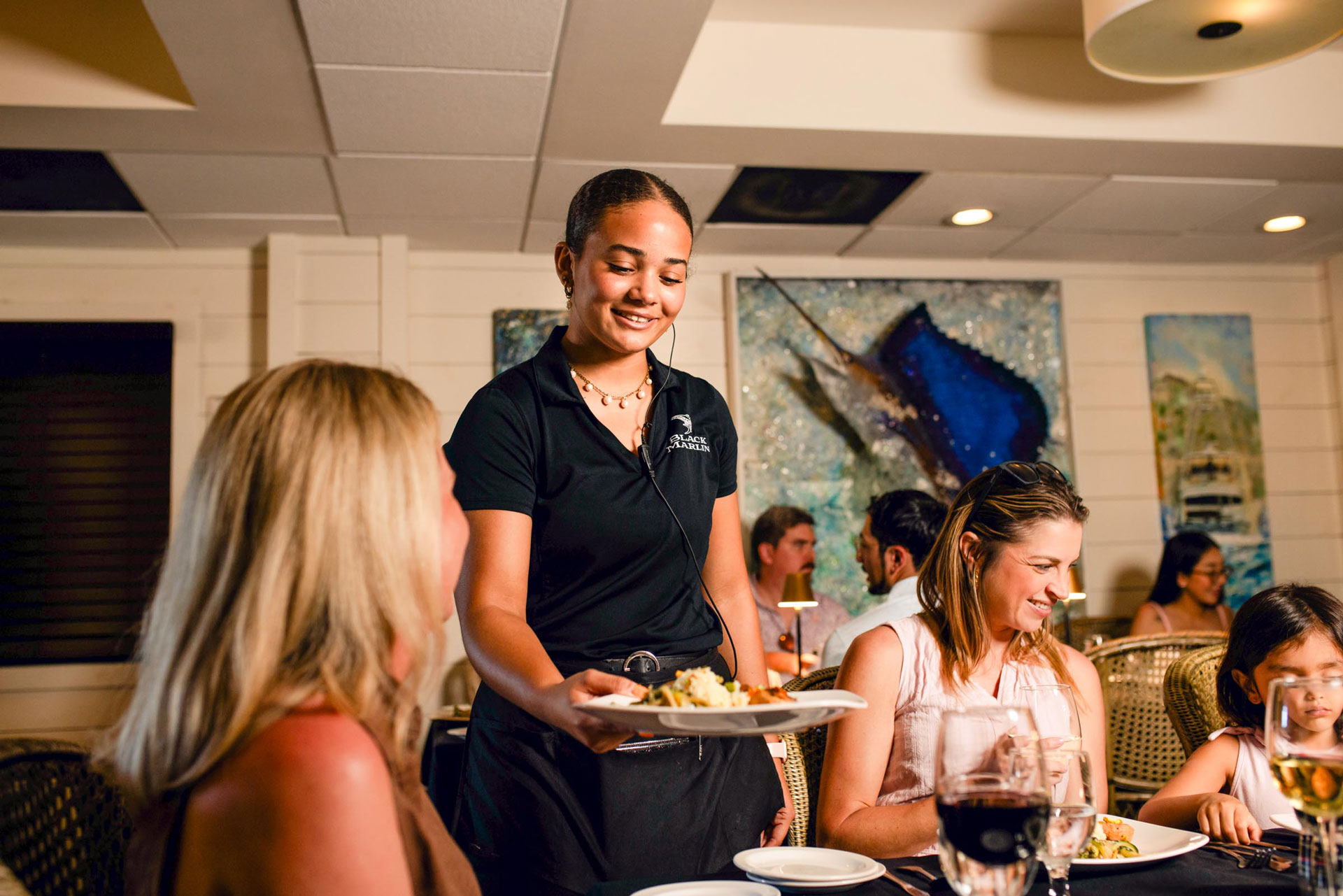 Server carrying a plated dish through the dining room at The Black Marlin