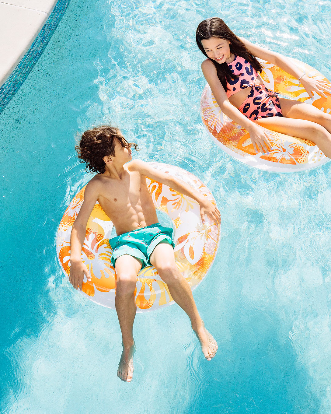 Two kids floating on inner tubes in a turquoise resort pool