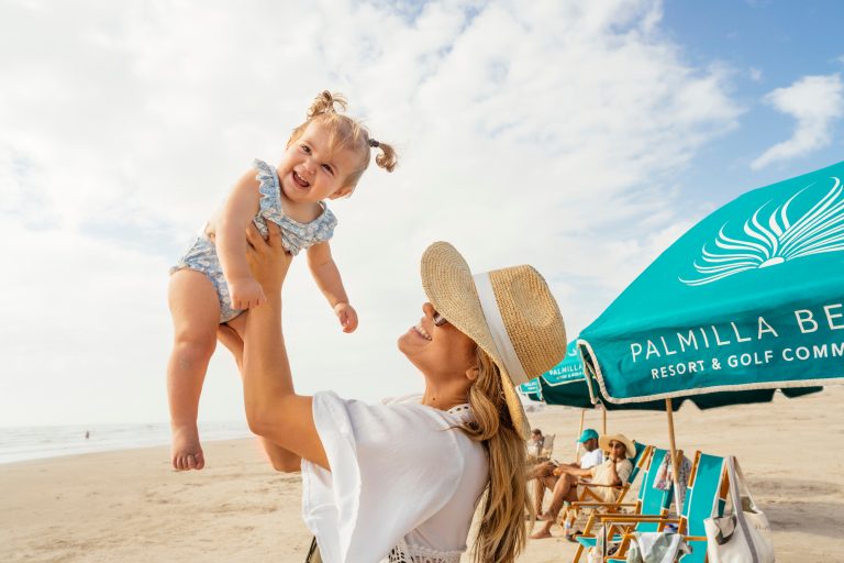 Family playing under a Palmilla Beach umbrella on the sand
