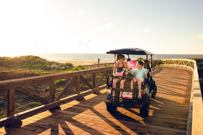 Guests arriving at a Palmilla Beach stand with a golf cart