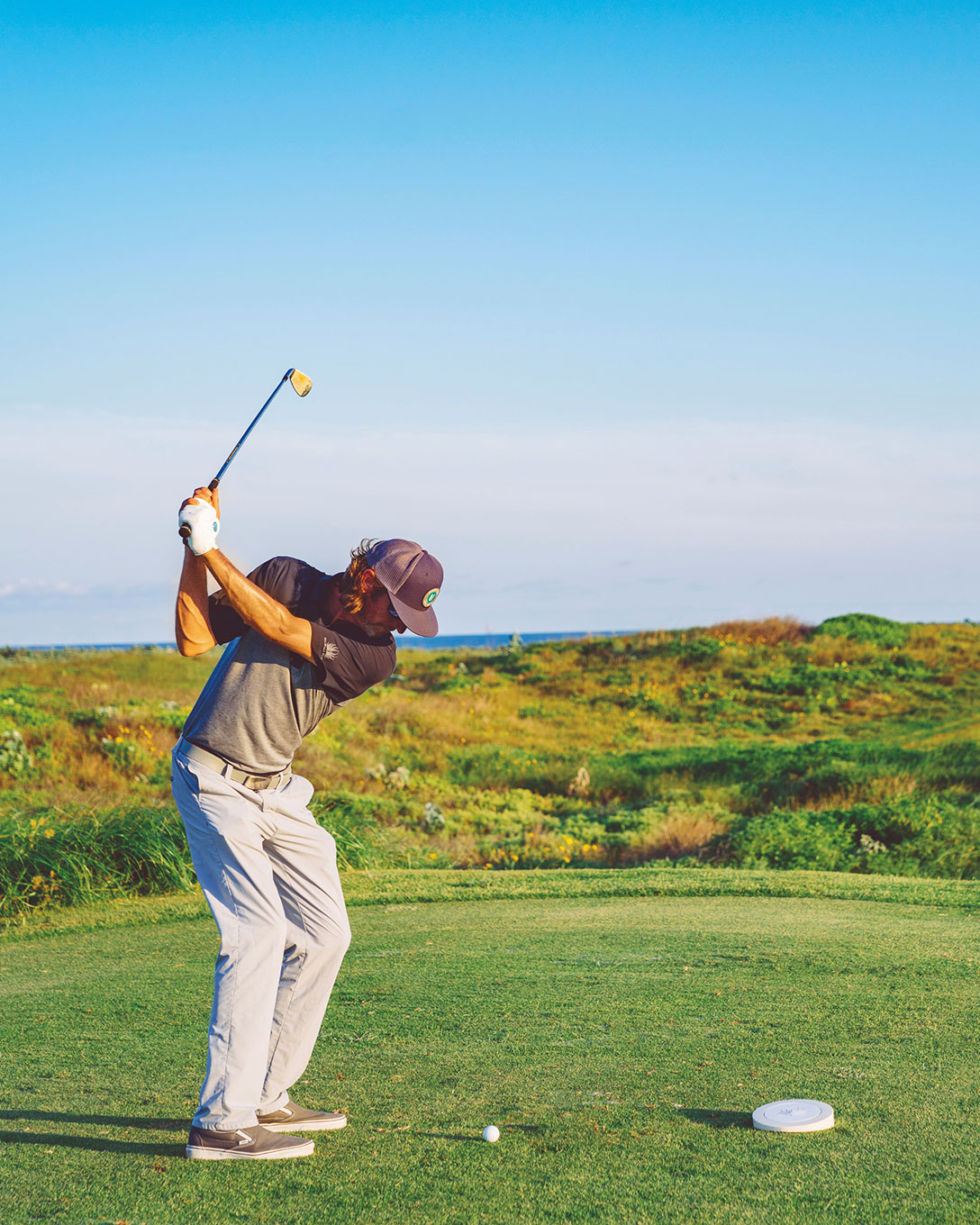 Golfer swinging on a coastal tee box at Palmilla Beach