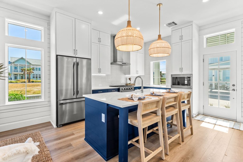 Kitchen with a navy island, rattan pendants and barstools at 101 Sea Whip Lane