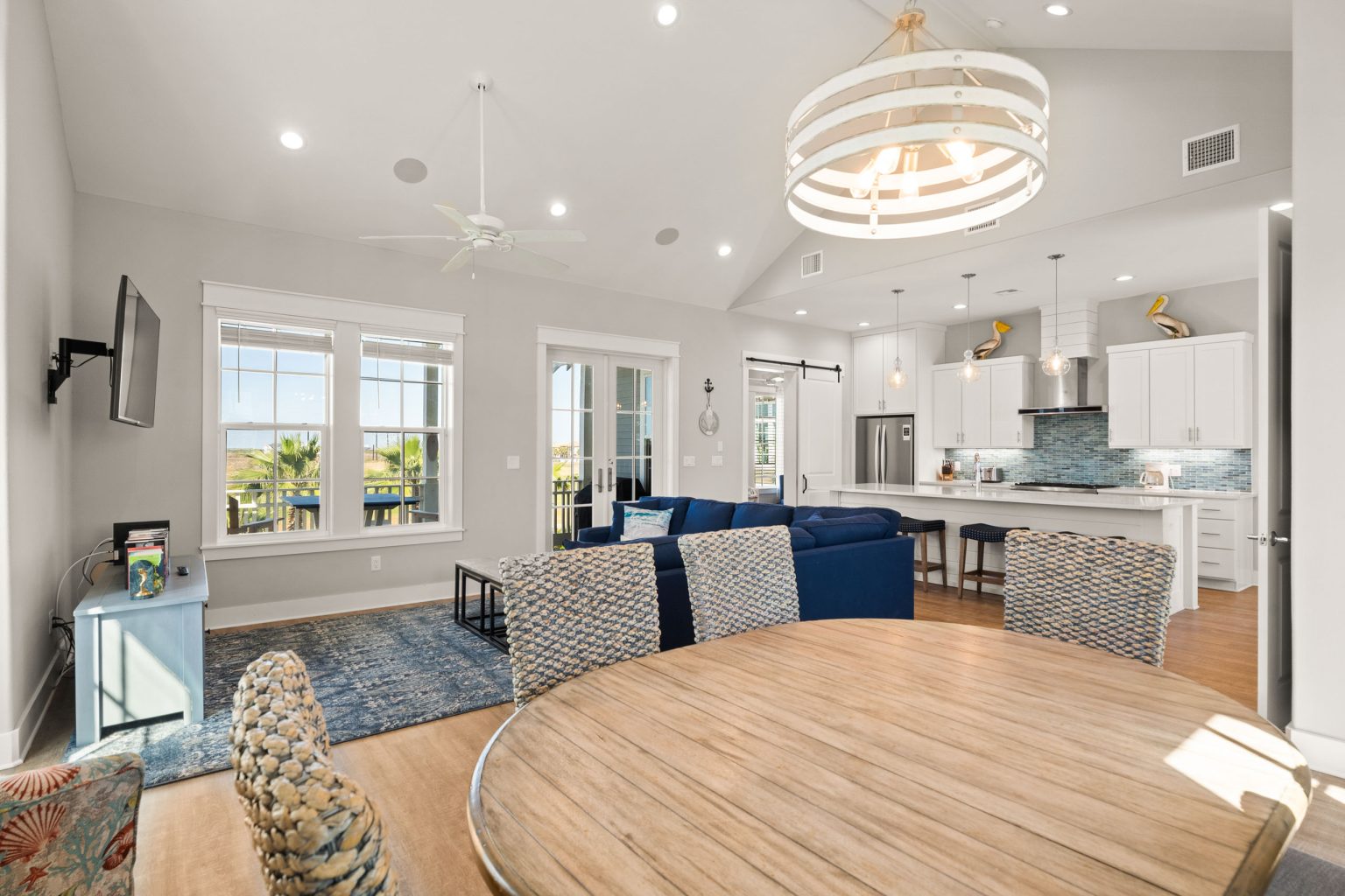 Dining table under a round chandelier, open to the living room at 200 Sunset Avenue