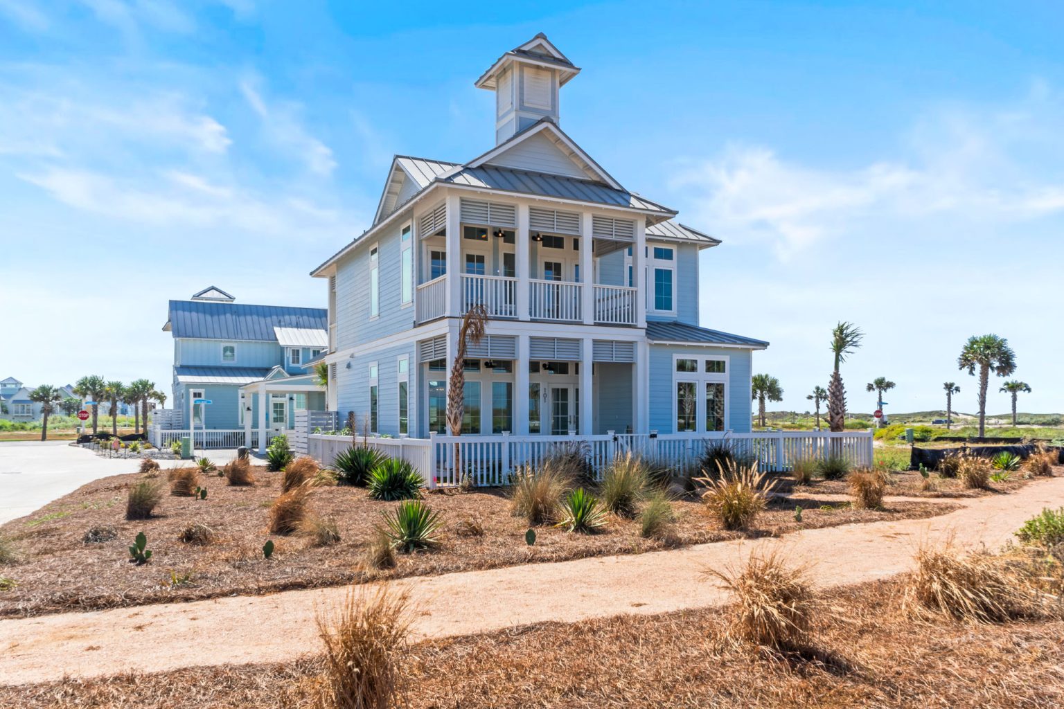 Front of 101 Sea Whip Lane, a light blue home with a cupola and double porches at Palmilla Beach