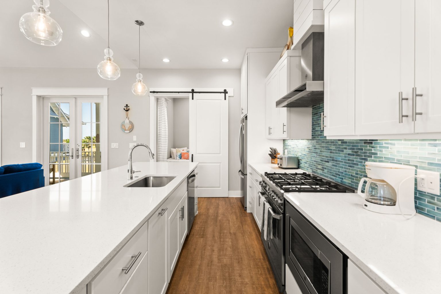 Kitchen island and gas range with blue glass tile backsplash at 200 Sunset Avenue