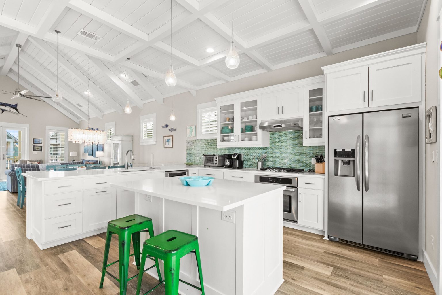 Kitchen with a white island, green stools and stainless refrigerator at 152 Sea Rocket Lane