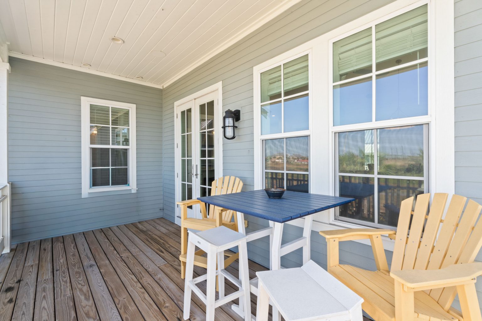 Covered back porch with dining table and Adirondack chairs at 200 Sunset Avenue