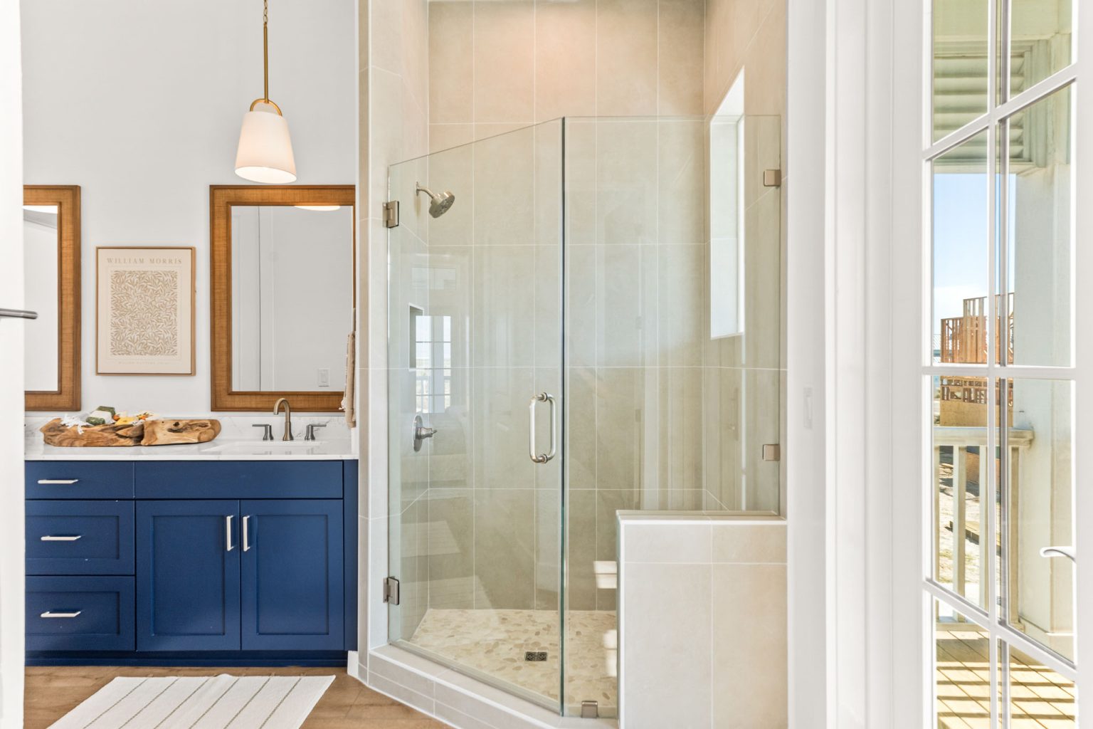 Primary bathroom with a navy double vanity and glass shower at 101 Sea Whip Lane