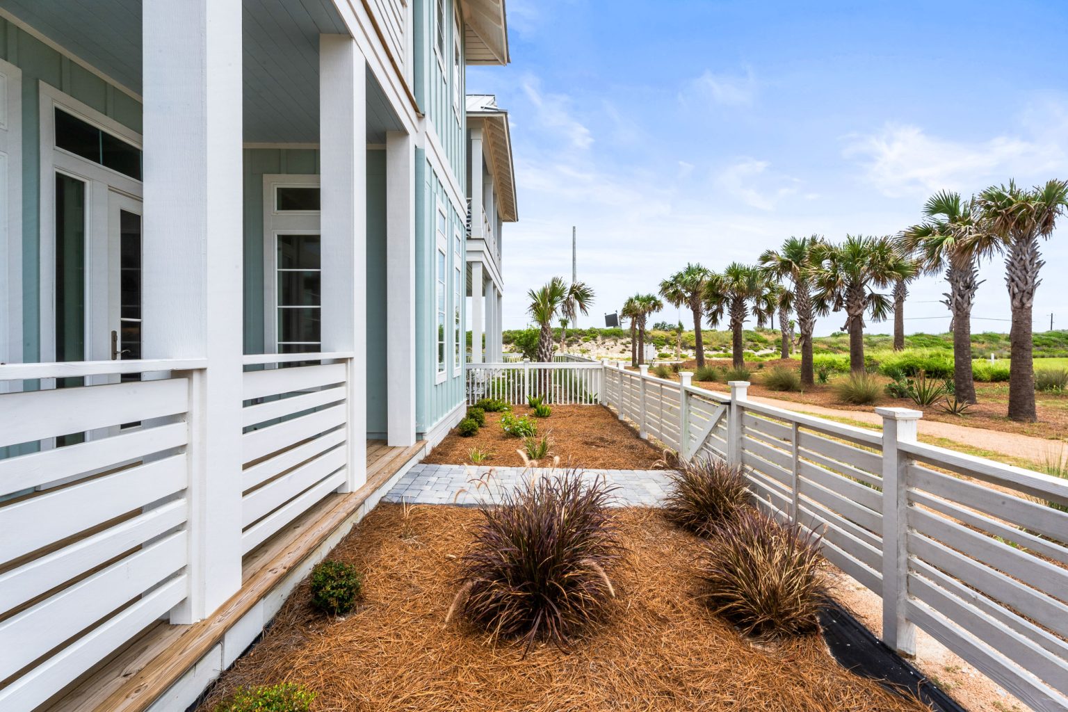 Side porch and landscaped yard with palms at 120 Lotus Lane