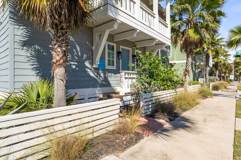 Side yard with palms and a white privacy fence at 200 Sunset Avenue