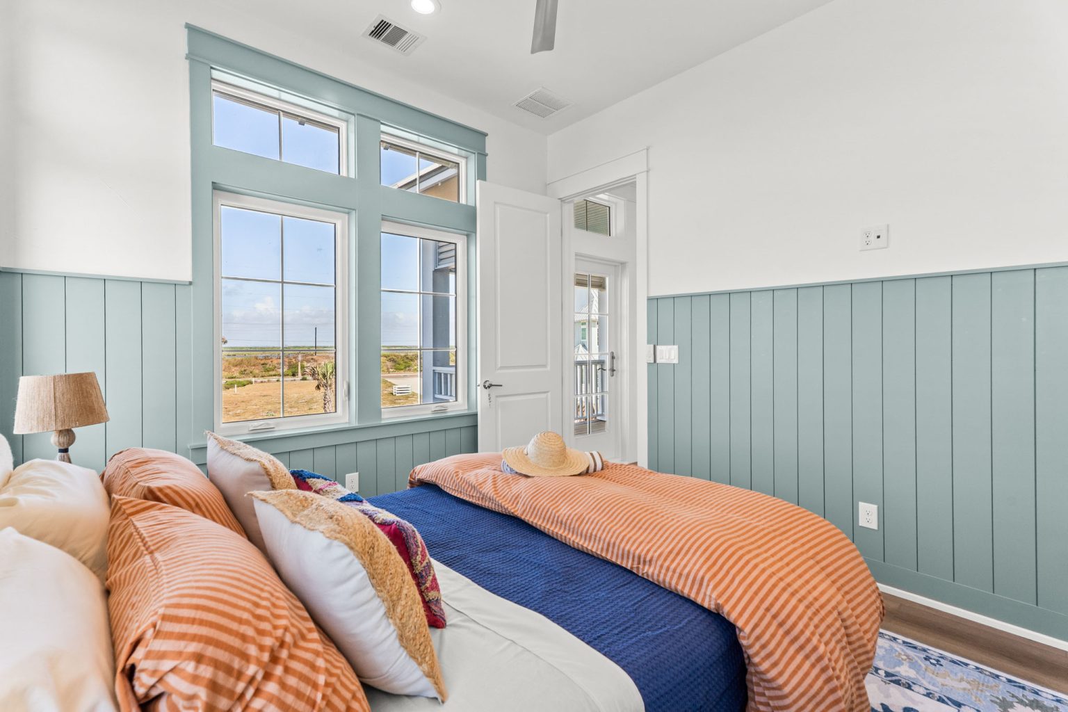 Bedroom with sage paneled walls and orange bedding at 101 Sea Whip Lane