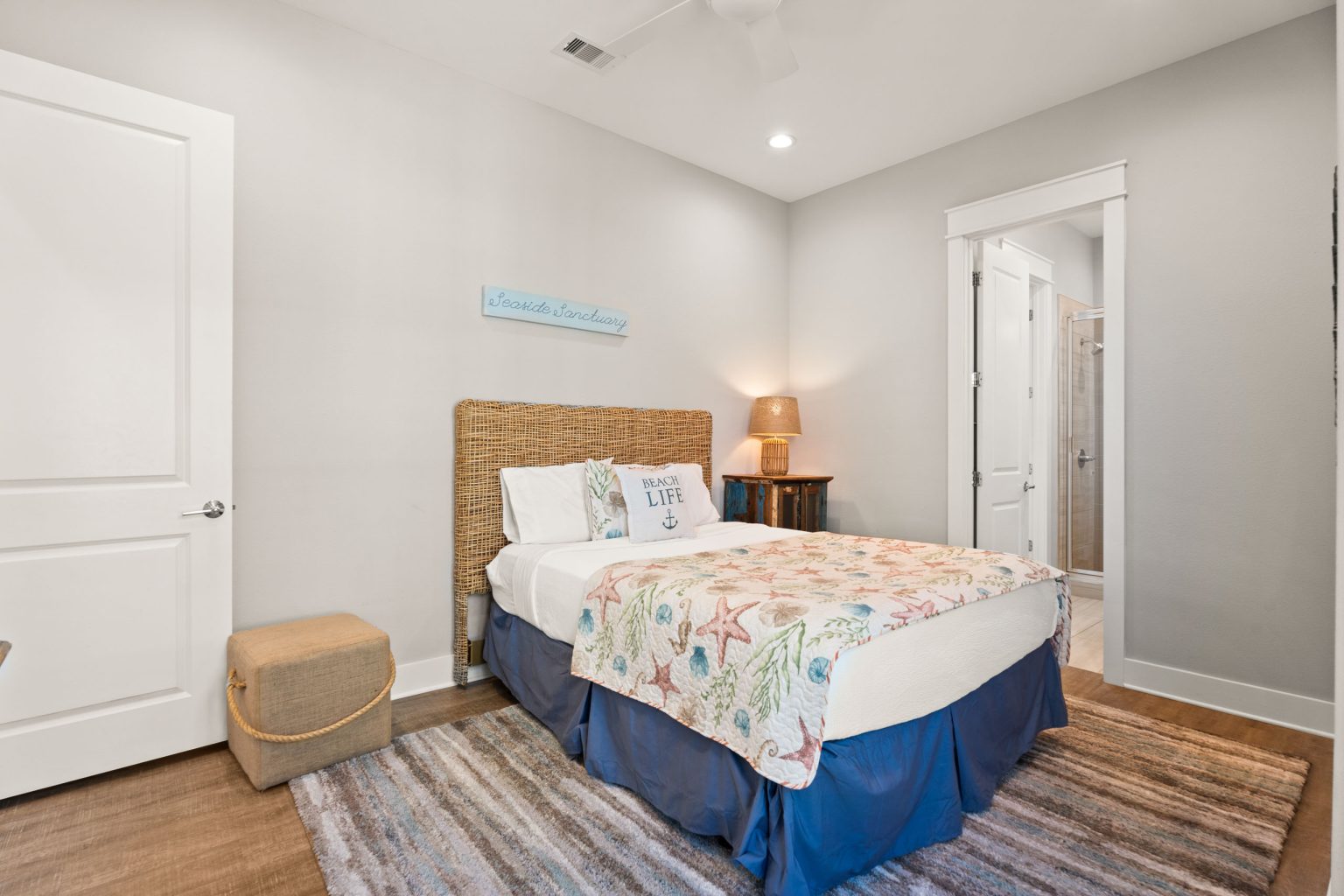 Bedroom with a woven headboard and coastal bedding at 200 Sunset Avenue