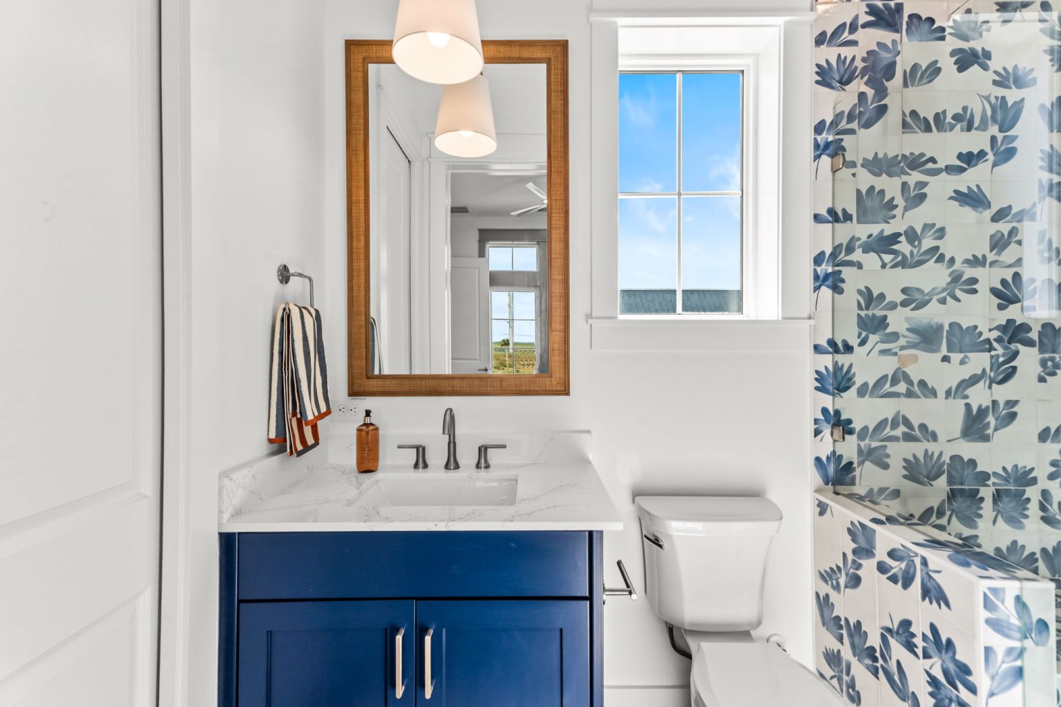 Bathroom with a navy vanity and leaf-pattern wallpaper at 101 Sea Whip Lane