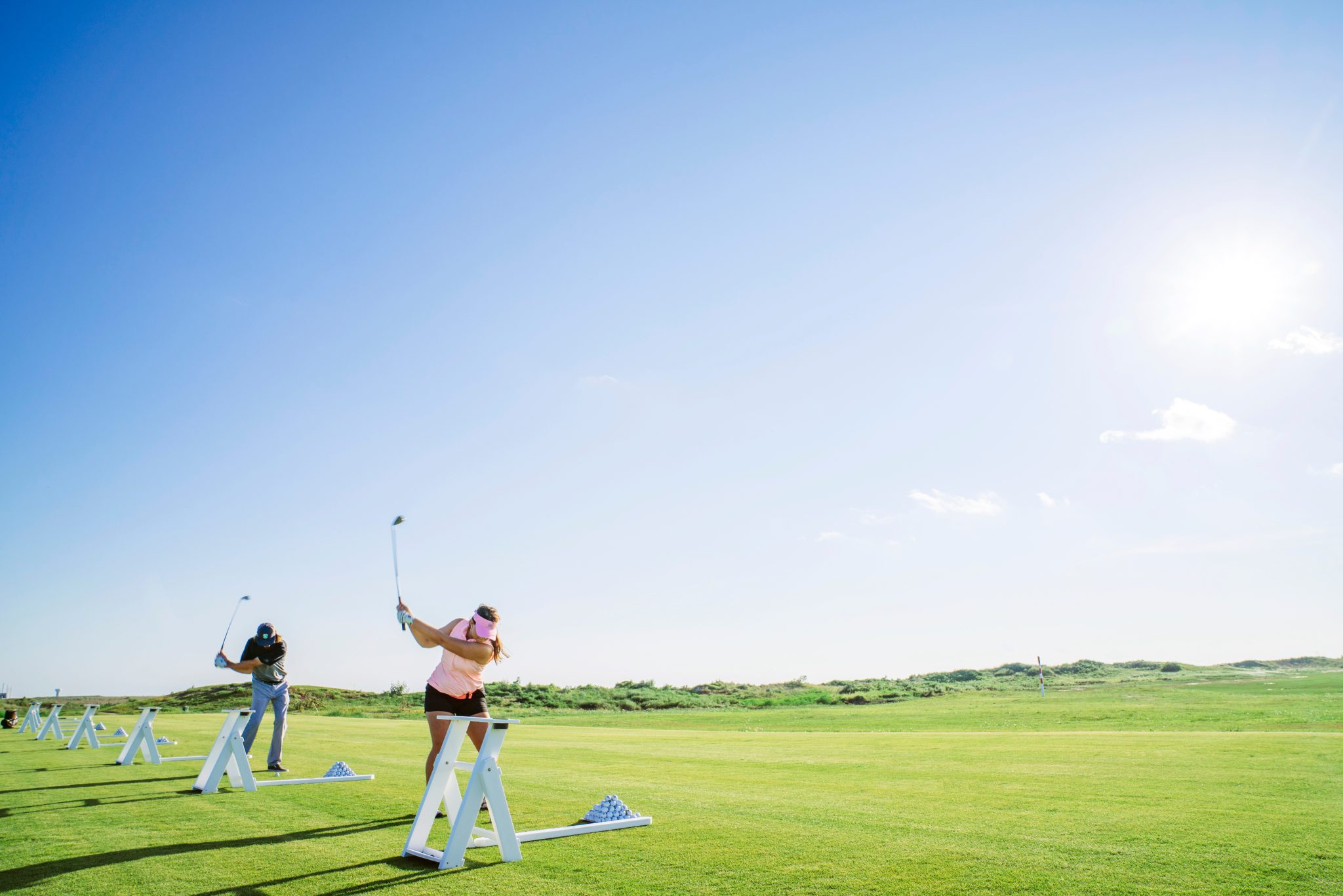 Golfers practising their swings on the Palmilla Beach driving range under a blue sky