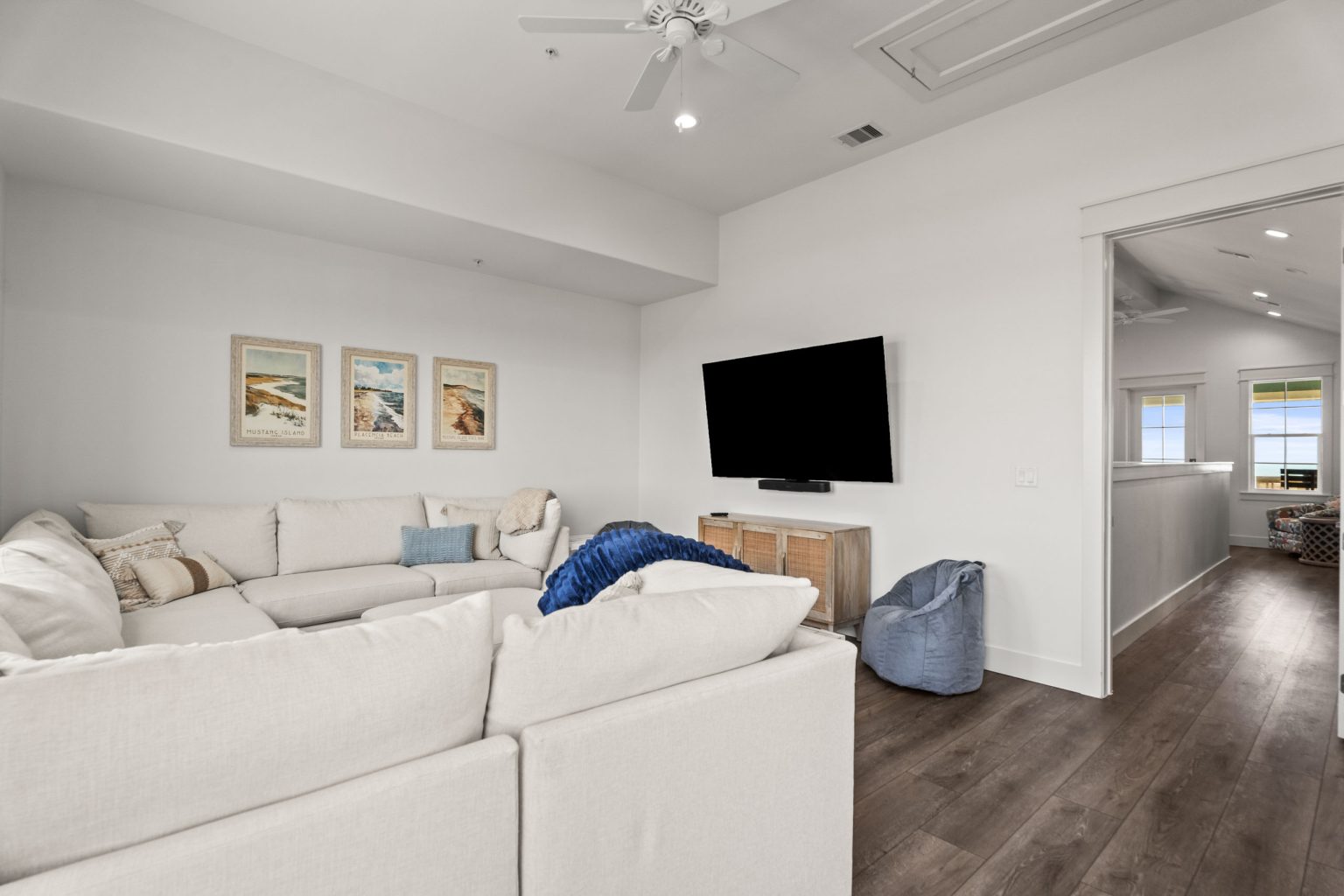 Media room with a white sectional and wall-mounted TV at 250 Sunrise Avenue