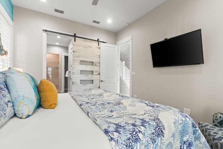 Bedroom with a sliding barn door and wall-mounted TV at 152 Sea Rocket Lane