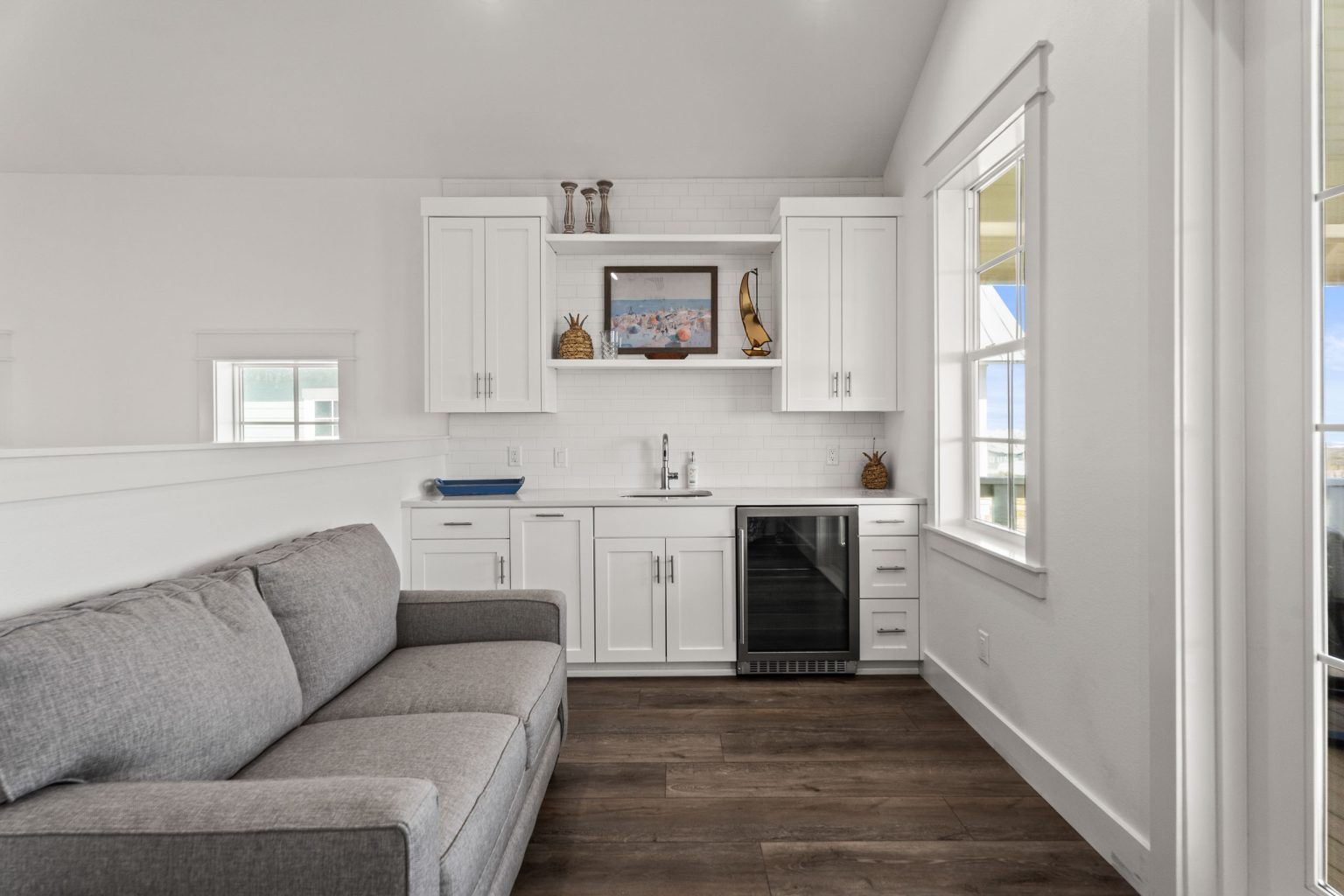 Wet bar with beverage fridge and gray sofa at 250 Sunrise Avenue