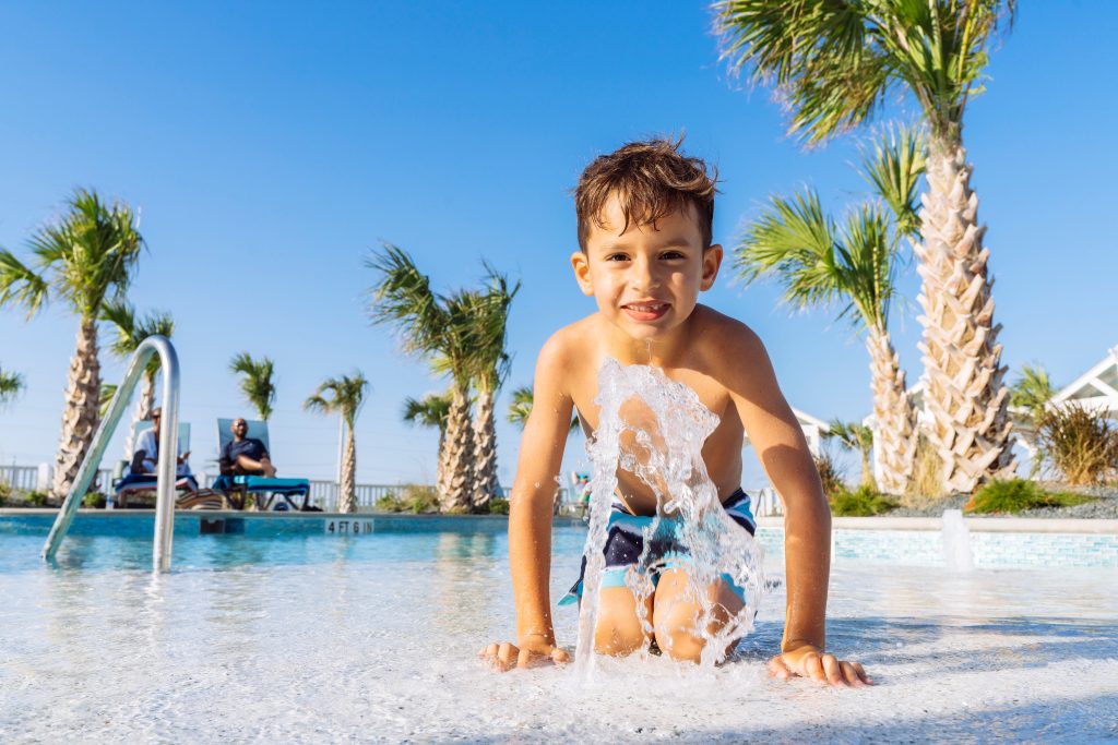 A boy playing in the splash fountain at the Palmilla Beach resort pool