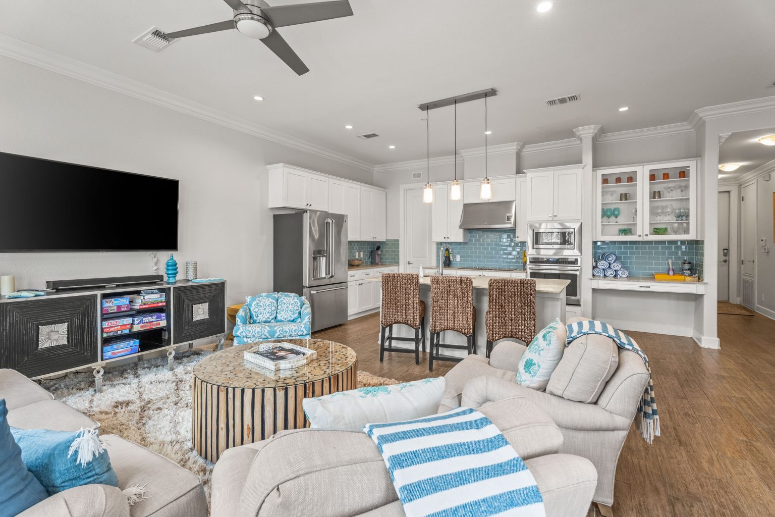 Living room with a large TV, sofa and kitchen beyond at 137 Palmilla Circle #204