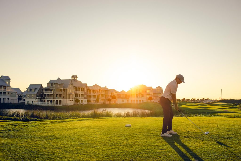 A golfer teeing off at sunset on the Palmilla Beach golf course
