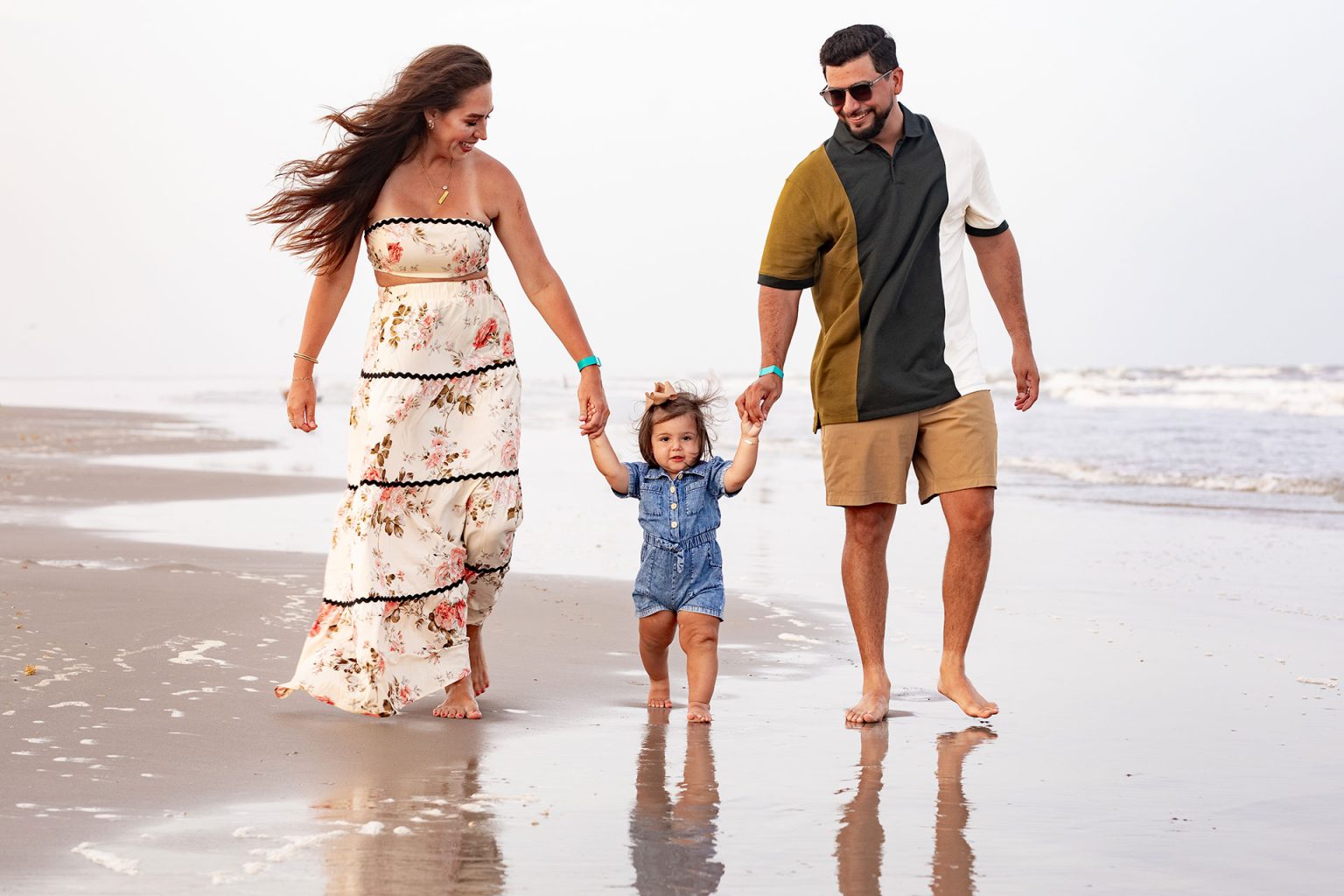 Parents walking hand in hand with their toddler at the water's edge