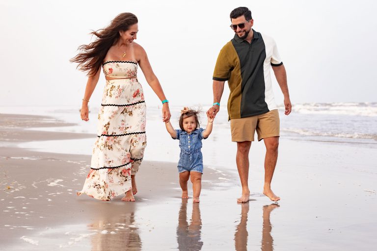Parents walking hand in hand with their toddler at the water's edge