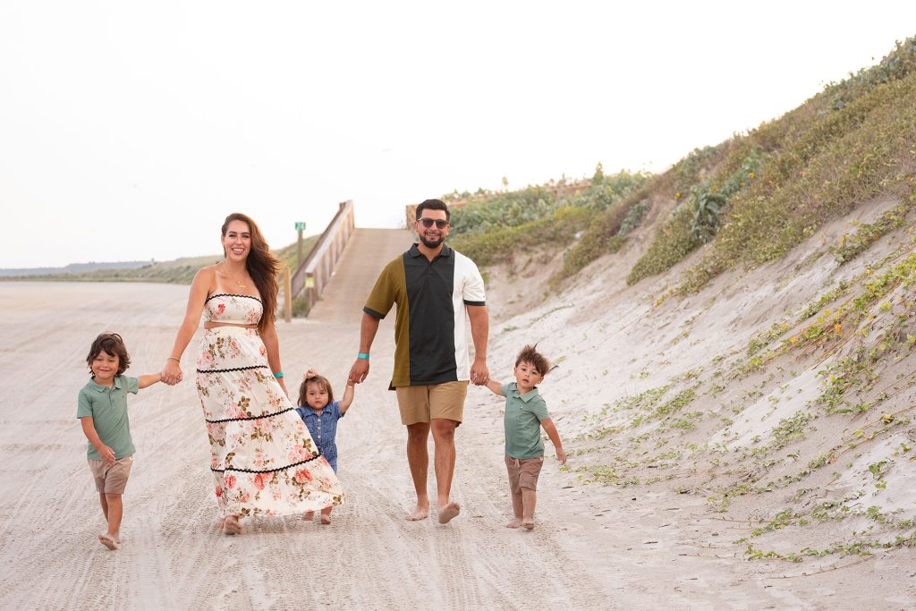 Family holding hands on a sandy path through the dunes