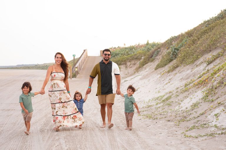 Family holding hands on a sandy path through the dunes