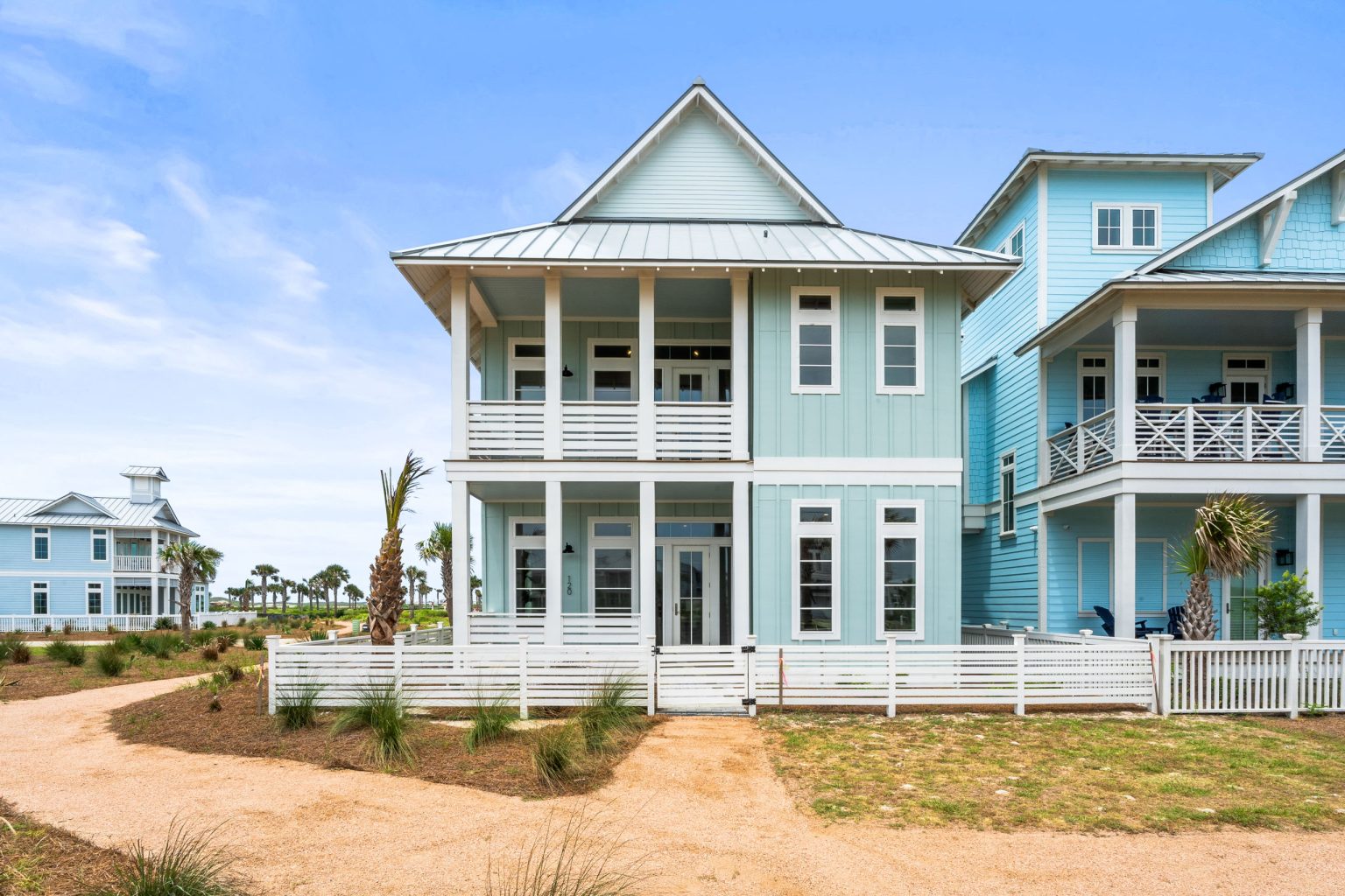 Front of 120 Lotus Lane, a two-story light blue home with double porches at Palmilla Beach