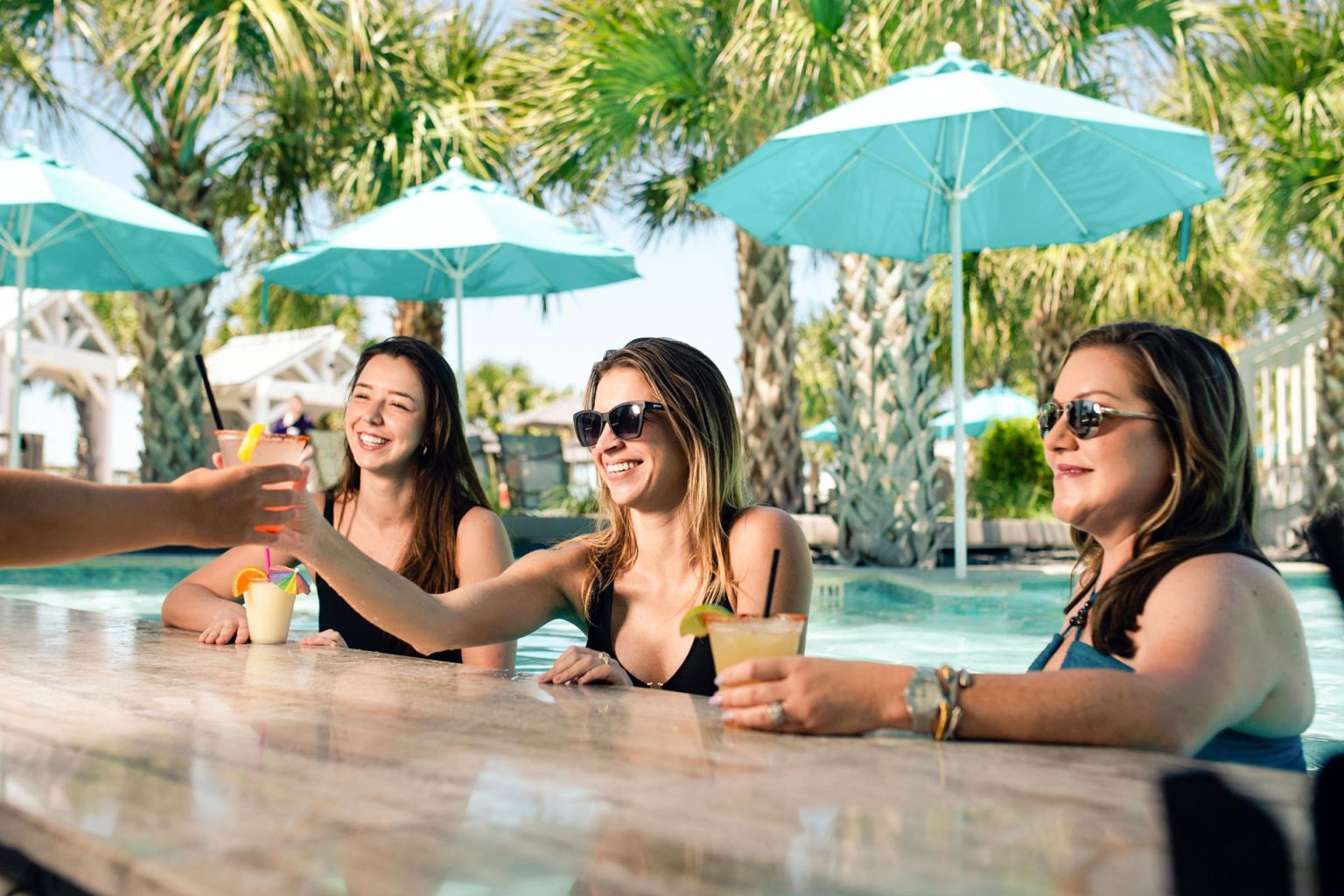 Friends toasting with drinks at The Oasis swim-up bar