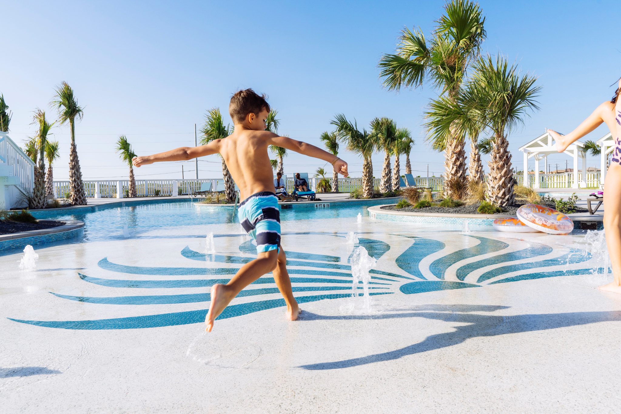 A boy jumping through the splash fountain at the Palmilla Beach resort pool
