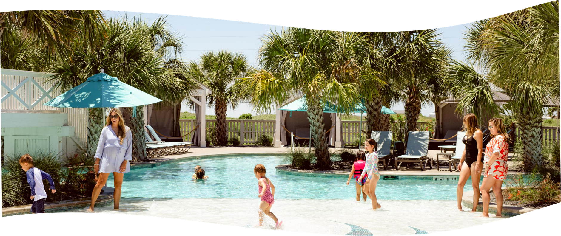 Families playing in the resort pool under palm trees at Palmilla Beach