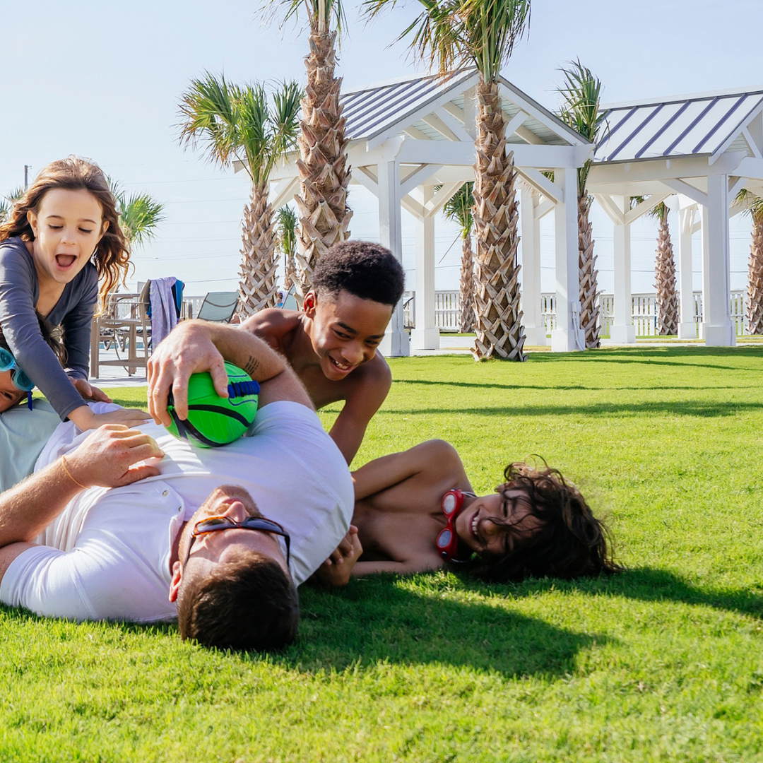 Family playing together on the lawn at Palmilla Beach