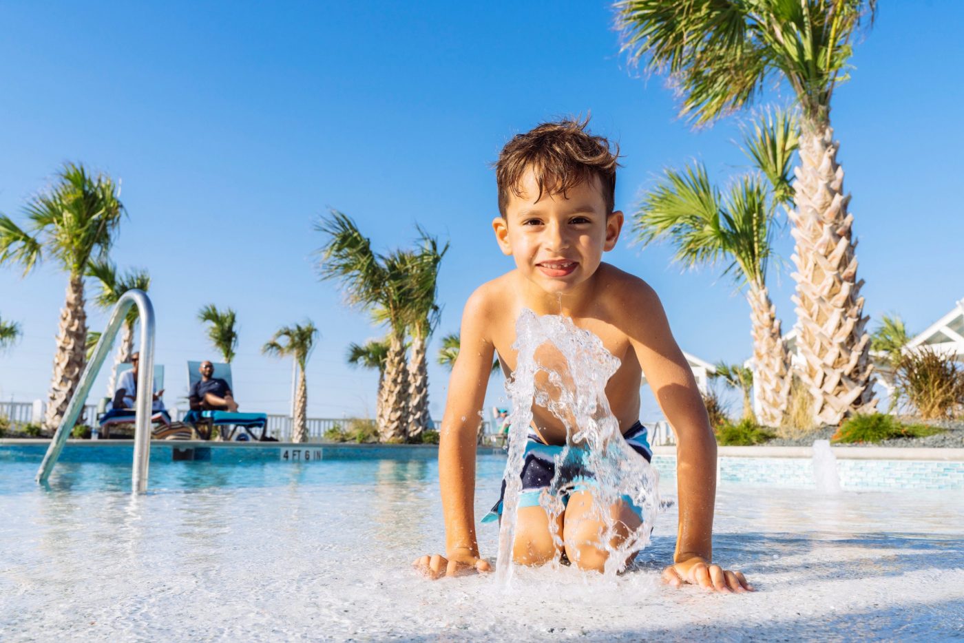 A boy playing in the splash fountain at the Palmilla Beach resort pool