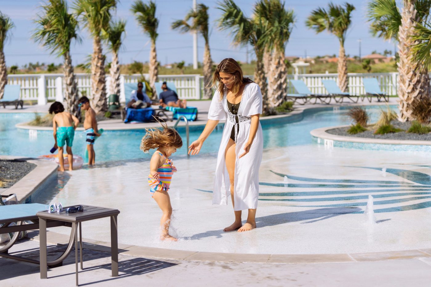 A mother and toddler splashing at the zero-entry edge of The Oasis pool