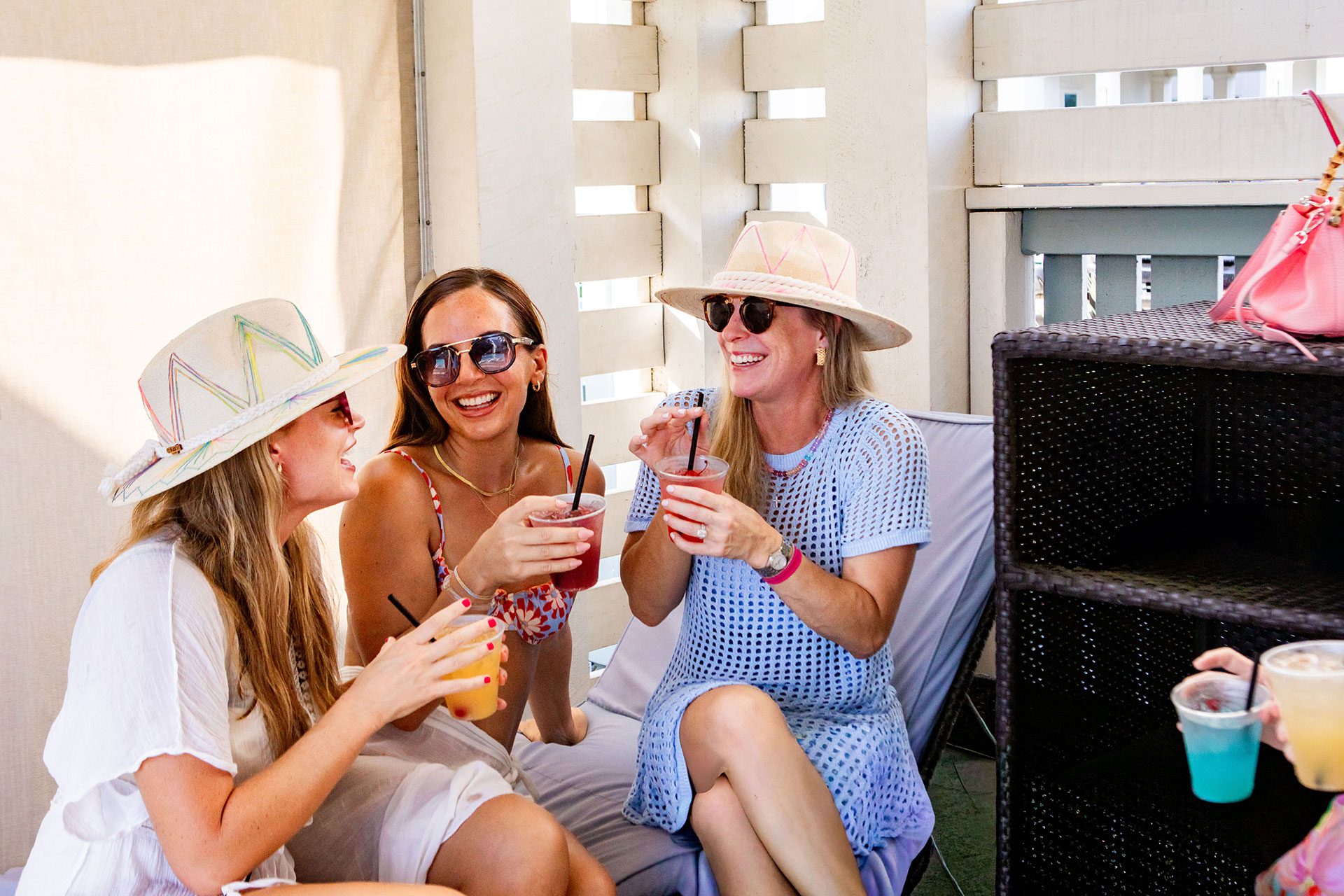 Friends sharing drinks in a shaded poolside cabana